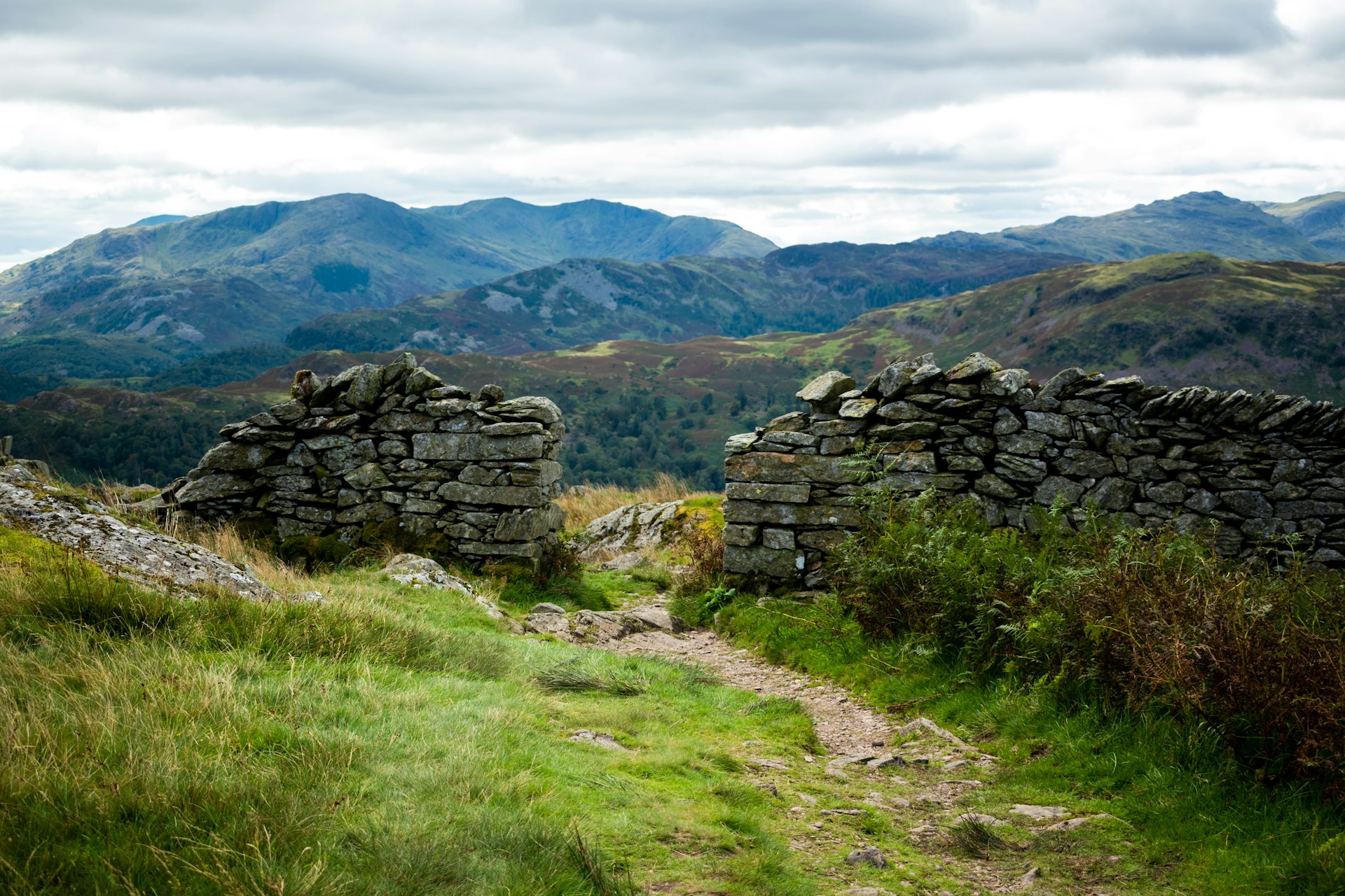 Remains of dry stone wall in gree fields against backdrop of hills